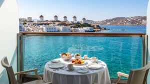 7 Best Greek Islands Cruises: #1 Ultimate Mediterranean Guide 2 Traveler enjoying breakfast on a cruise balcony overlooking Mykonos