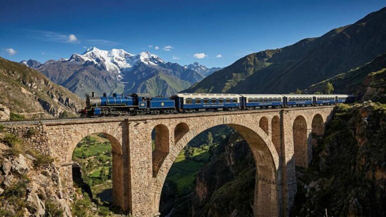 A luxury andean rail travel vintage train crossing a high stone bridge in the Andes mountains.