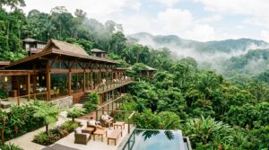 Horizontal panoramic view of a luxury eco-lodge surrounded by lush tropical rainforest.