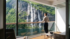 A traveler on a cruise balcony looking at the Seven Sisters waterfall in Norway